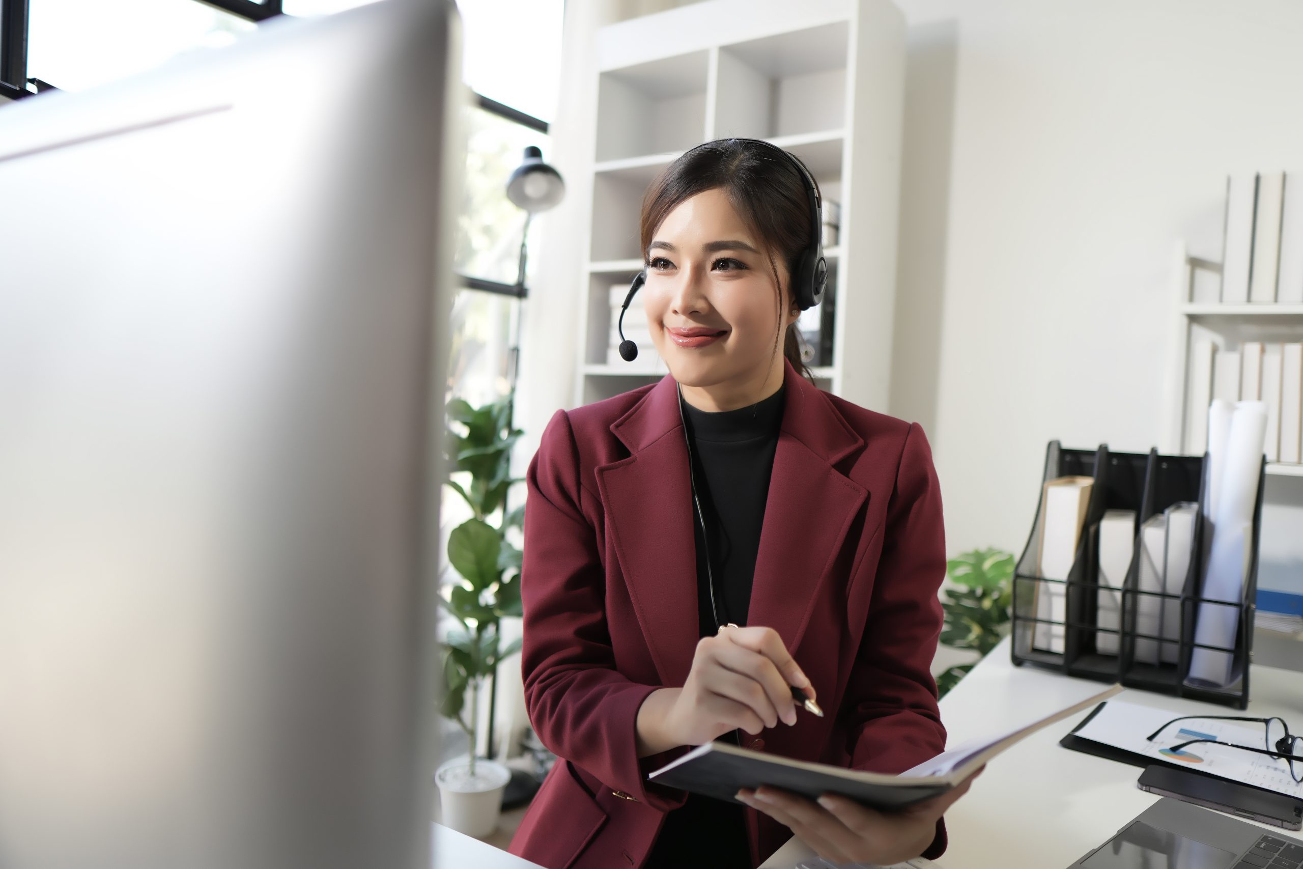 Portrait of a cheerful young woman working as a call center operator, wearing headphones and holding a microphone.